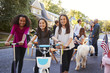 © Monkey Business - Three pre-teen girls on scooters and a bike at a block party