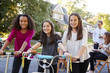 © Monkey Business - Three pre-teen girls on scooters and a bike at a block party