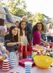 Pre-teen girls smiling to camera at a block party food table