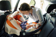 Happy woman with infant seating in baby chair in car