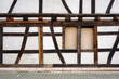 Fachwerkfassade / Die Balkenkonstruktion und das Holzgerüst eines Fachwerkhauses mit zugenageltem Fenster.