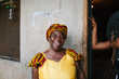 © Julia Forsman/Stocksy - African woman in her sixties laughs by the door of her home.