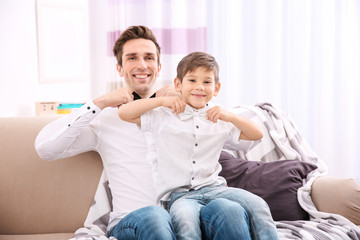 Poster - Father and son in shirts with bowties sitting on sofa at home