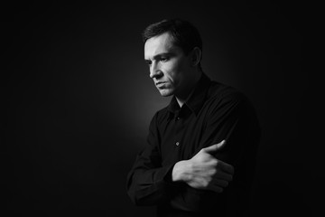 Serious young man on dark background, black and white effect