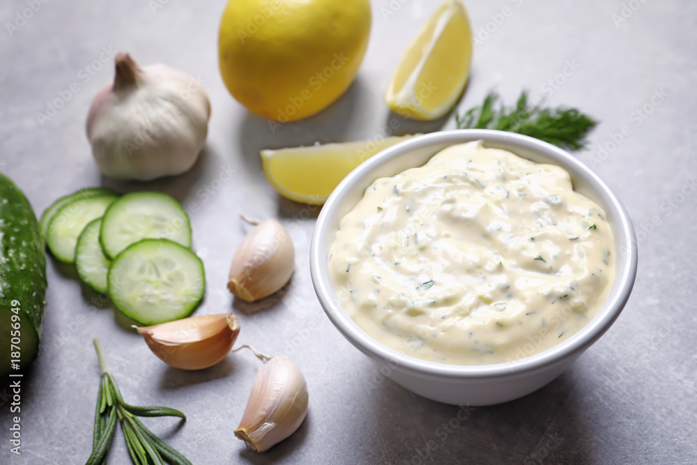 Tasty sauce with garlic in bowl and ingredients on table