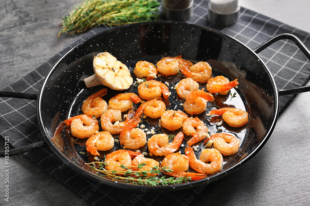Dish with delicious fried shrimps and garlic on table