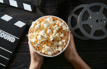 Wall Mural - Woman holding paper cup with tasty popcorn, top view