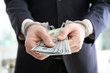 © Africa Studio - Businessman in handcuffs holding bribe on blurred background