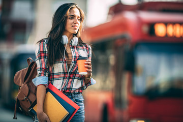 Young woman traveler waiting for a bus on a bus station, travel and active lifestyle concept.