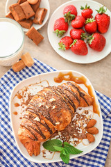 Yummy croissant with caramel and chocolate toppings served for breakfast on table