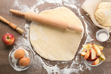 Wall Mural - Raw dough and ingredients for apple pie on table