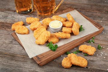 Canvas Print - Wooden board with tasty chicken nuggets and sauce on table