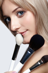 Blonde beauty female stylist - visagist with makeup brushes