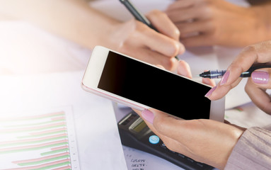 two business woman hand writing and using mobile phone for their work  analyzing on financial project with business graph ,data and calculator on desk 