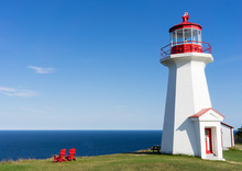A Lighthouse Over-looking The Blue Ocean On The Gaspesie Peninsula Of Quebec In Canada On A Warm And Sunny Day.