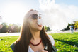 © mnelen.com - Happy fashion smiling Woman in sunglasses smoking vape on street,smoke