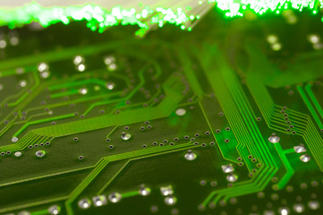 Green circuit board close up shot, defocused optical fibre in the background