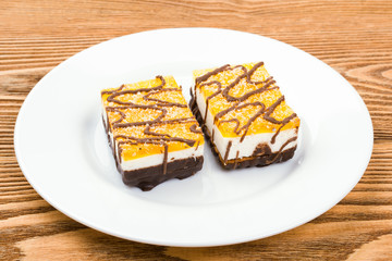 Two chocolate cakes on a white plate on a wooden background 