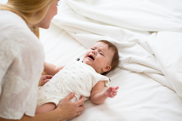 Portrait of a newborn baby crying in front of her mother