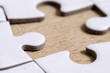 © marinzolich - the gap and the solution, white jigsaw/puzzle with one gap, over wooden table background, symbol of problem solving