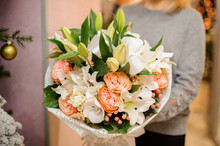 Female Holds A Bouquet Lilies, Orchids, Pion-shaped Roses In White Wrapping Paper