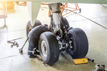 repair of the chassis landing gear of the aircraft, two technicians of mechanics at work in the hang