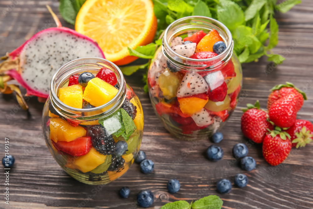Jars with delicious fruit salad on wooden table