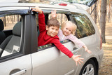 Fototapeta  - Adorable little children leaning out of car window