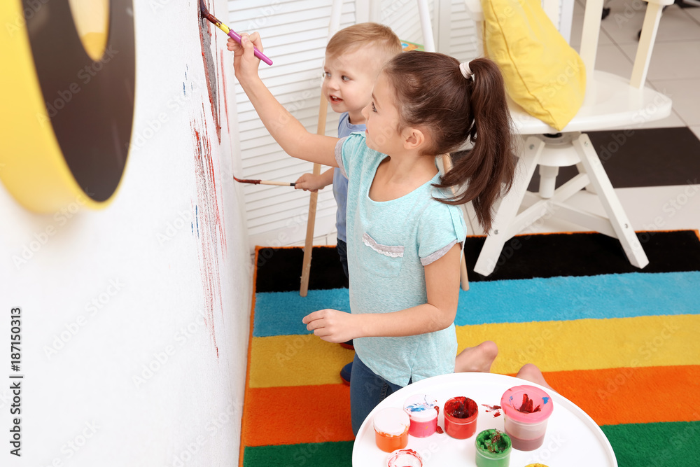 Little children painting on wall at home