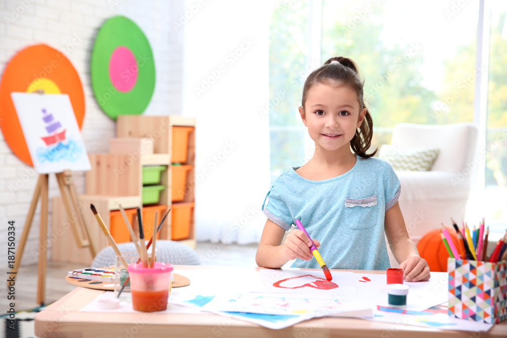 Little girl painting at table indoors