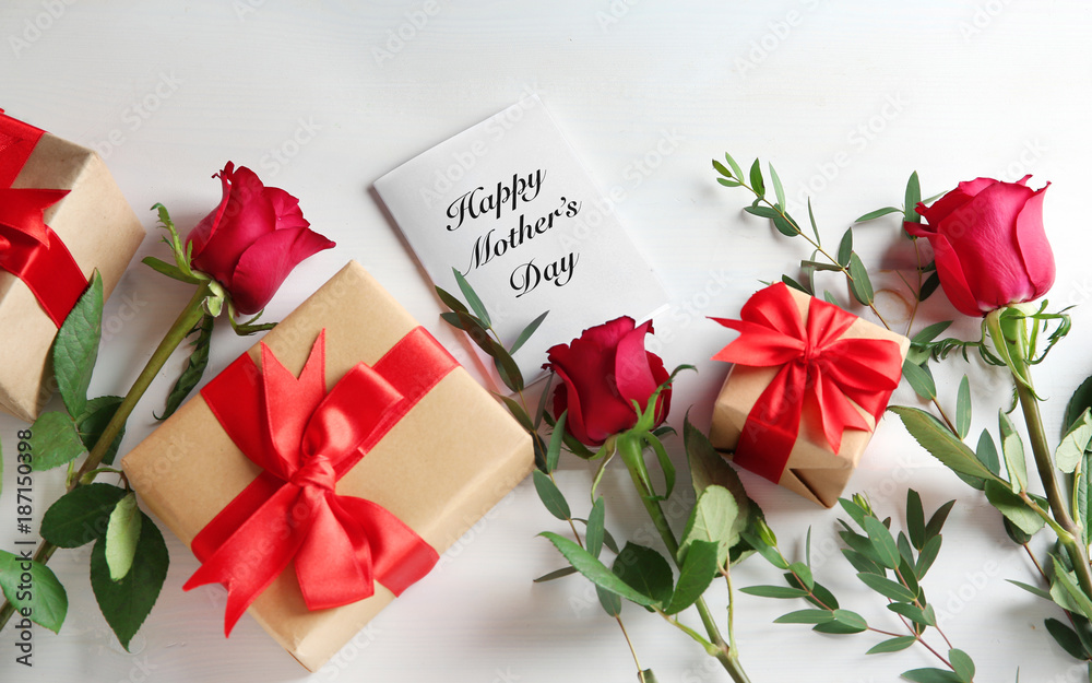 Composition with red roses, gift boxes and greeting card on light background. Mother's Day composition