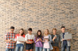 © Africa Studio - Group of cool teenagers with modern devices near brick wall