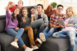 © Africa Studio - Group of teenagers with modern devices taking selfie while sitting on sofa indoors