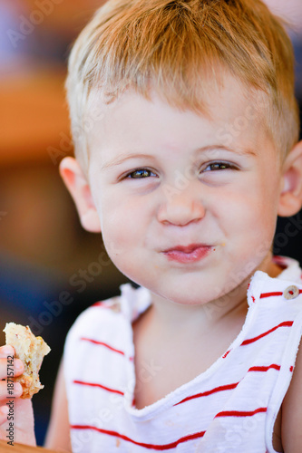 Photographie Portrait of blonde caucasian child eating a piece of bread