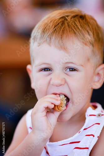 Photographie Portrait of blonde caucasian child eating a piece of bread