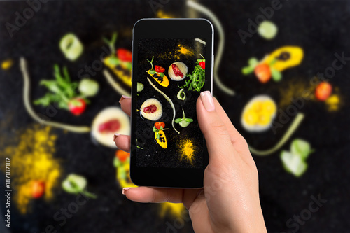 Fotomural Closely image of female hands holding mobile phone with photo camera mode on the