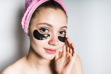 Wall Mural - girl with a towel on her head puts on her face a black mask