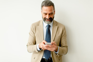 Wall Mural - Handsome mature businessman with mobile phone in the office