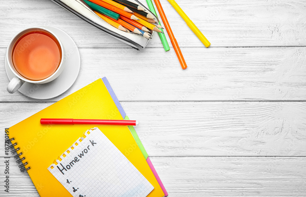 Sheet of paper with word "Homework", tea and stationery on wooden ...