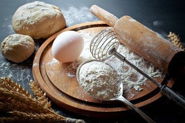 Wall Mural - Dough with flour on an old background in a composition with kitchen accessories