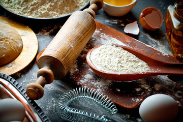 Wall Mural - Dough with flour on an old background in a composition with kitchen accessories