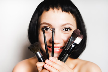 Wall Mural - girl with black hair smiling holding a set of brushes