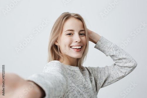 Fotografía Attractive dark-eyed blonde female dressed casually having delightful look smiling broadly