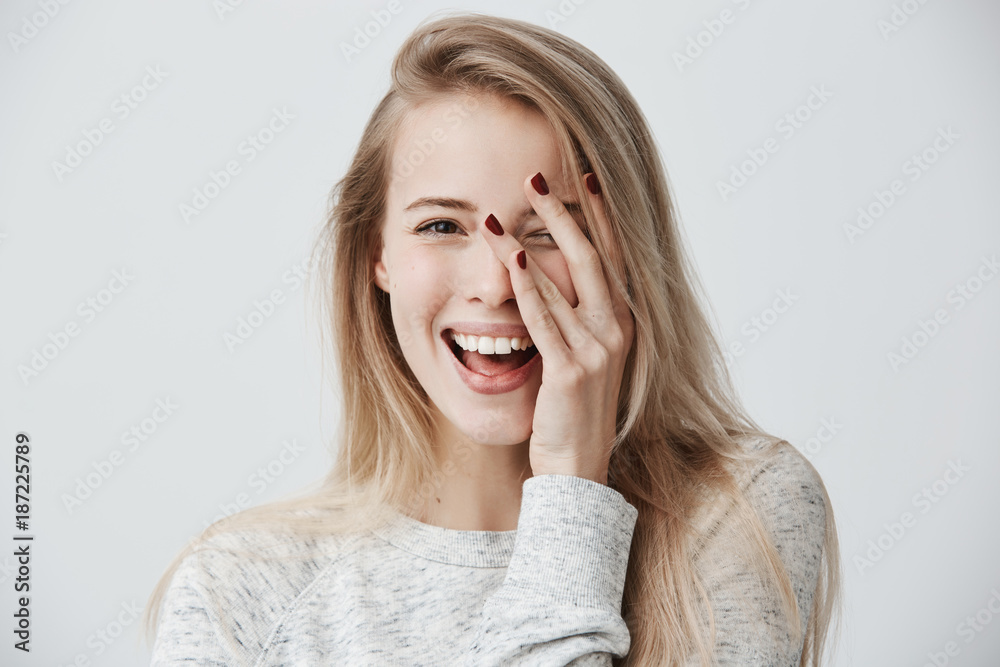Headshot of cute woman with dark eyes, blonde long hair, happy gentle smile rejoicing her success. Cheerful woman having birthday having pleased expression and pleasure. Face expressions - obrazy, fototapety, plakaty 