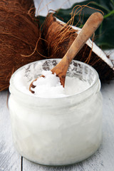 Wall Mural - coconut and opened glass jar with fresh coconut oil on wooden background.