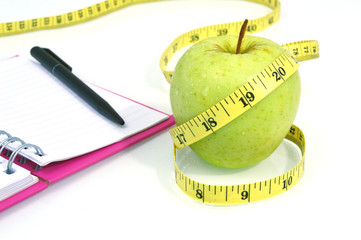 Green apple with measuring tape on white background