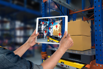 Industrial 4.0 , Augmented reality and smart logistic concept. Hand holding tablet with AR application for check order pick time around the world and supply chain in smart factory background.