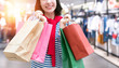 © zapp2photo - Shopping woman in winter shirt and red scarf holding shopping bags with smart retail fashion shop background. Smile shopper. online shopping concept. Flare light effect.