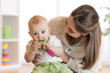 © Oksana Kuzmina - Baby sitting on mom knees bites toy