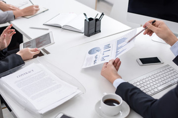 High angle close up of unrecognizable business people discussing statistics report  looking at charts and graphs with financial data during meeting in modern office